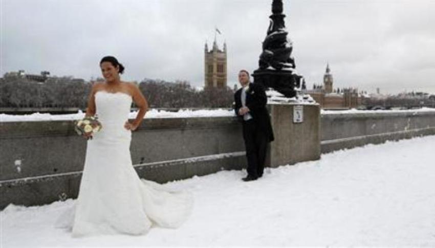 A newly married couple pose for a photograph in the snow opposite the Houses of Parliament, in central London, in this Dec. 18, 2010 file photo.