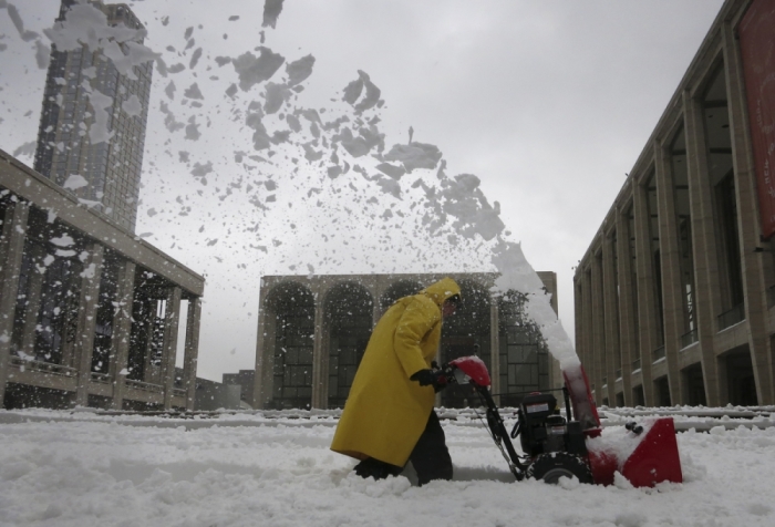 A worker uses a snow blower to clear snow in the Manhattan borough of New York February 13, 2014.