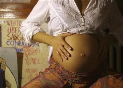 A pregnant woman displays her belly.