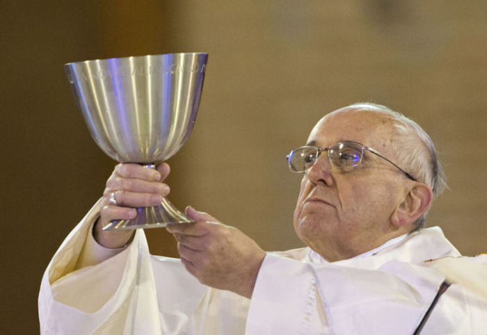 Pope Francis raises a large chalice.