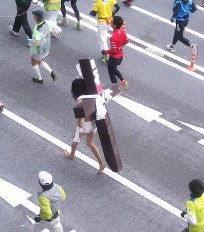 A man seemingly dressed as Jesus, with a large cross strapped to his back, ran in the Tokyo Marathon on February, 23. 2014.