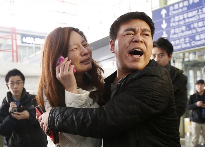A relative (woman in white) of a passenger onboard Malaysia Airlines flight MH370 cries as she talks on her mobile phone at the Beijing Capital International Airport March 8, 2014. The Malaysia Airlines flight carrying 227 passengers and 12 crew lost contact with air traffic controllers early on Saturday en route from Kuala Lumpur to Beijing, the airline said in a statement. Flight MH 370, operating a Boeing B777-200 aircraft departed Kuala Lumpur at 12.21 a.m. (1621 GMT Friday) and had been expected to land in the Chinese capital at 6.30 a.m. (2230 GMT) the same day.