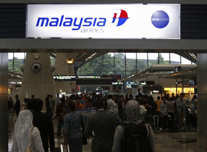 Passengers queue up at the Malaysia Airlines ticketing booth at the Kuala Lumpur International Airport in Sepang. A missing Malaysia Airlines jetliner may have turned back from its scheduled route before vanishing from radar screens, military officers said, deepening the mystery surrounding the fate of the plane and the 239 people aboard.