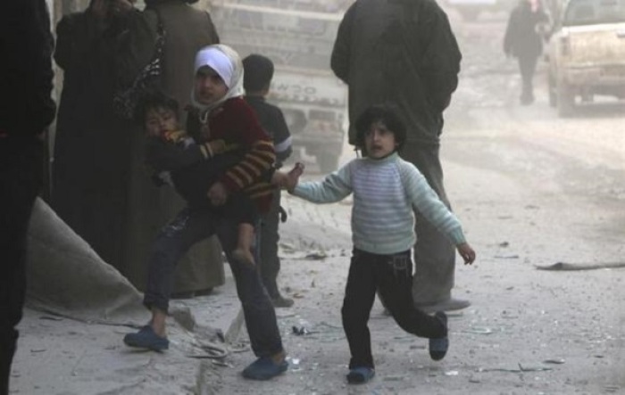 Children walk at a site hit by what activists said was a barrel bomb dropped by forces loyal to Syria's President Bashar al-Assad in Aleppo's al-Sakhour district March 6, 2014.