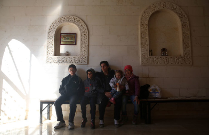 A Syriac Christian family from Syria waits at the entrance of the Mort Shmuni Syriac Orthodox Church in the town of Midyat, in Mardin province of southeast Turkey February 2, 2014. For longer than two years, not only the native Turkish Christian citizens of Midyat, but also the Syriac families escaping the bloody war in Syria just across the border are joining the congregation. Since then Sunday masses are more crowded, more enthusiastic. Picture taken February 2, 2014.
