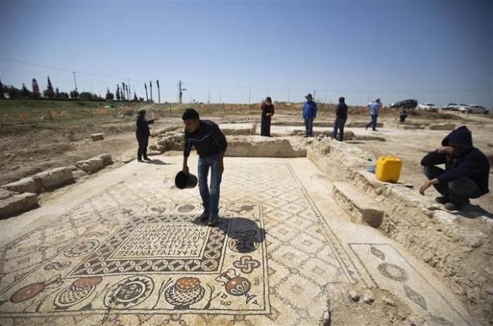 A worker for the Israel Antiquities Authority (IAA) stands on the mosaic floor of a monastery unearthed during excavations in Hura, east of Beersheba April 1, 2014.