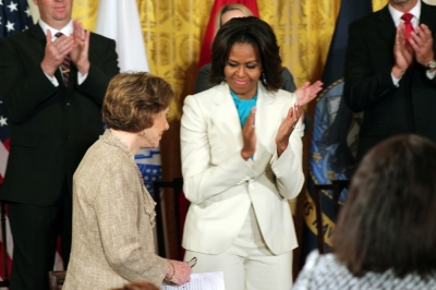 Former first lady Rosalynn Carter (L) heads to the podium as first lady Michelle Obama claps, for a Joining Forces event at the White House, Washington, D.C., April 11, 2014.