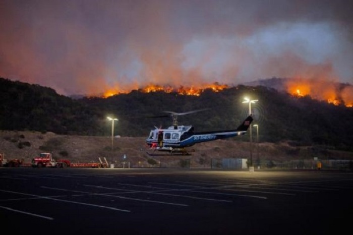 A helicopter is seen as firefighters battle a blaze in San Marcos, California May 14, 2014.