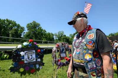 U.S. Army Veteran Lou Mitchell, 83, of Dale City, Virginia, with a U.S. flag in his cap, looks at a flower memorial for the 101st Airborne Division, with whom he served in Vietnam, at the Vietnam Veterans Memorial during Rolling Thunder XXVII on Memorial Day weekend to remember POWs and MIAs and honor the nation's military, in Washington, May 25, 2014.