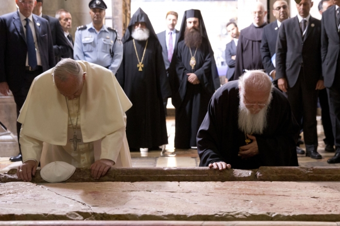 Pope Francis (L) and Constantinople Patriarch Bartholomew kneel at the Stone of Unction, traditionally claimed as the stone where Jesus' body was prepared for burial, in the Church of the Holy Sepulchre, in Jerusalem May 25, 2014.