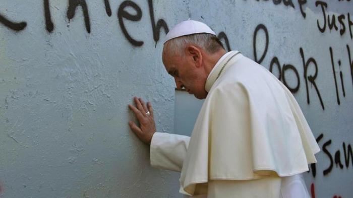 Pope Francis touches the wall that divides Israel from the West Bank, on his way to celebrate Mass in Manger Square next to the Church of the Nativity in the West Bank city of Bethlehem on May 25, 2014.