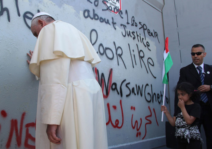 Pope Francis touches the wall that divides Israel from the West Bank, on his way to celebrate a mass in Manger Square next to the Church of the Nativity in the West Bank city of Bethlehem May 25, 2014. Pope Francis made a surprise stop at the hulking wall Palestinians see as a symbol of Israeli oppression on Sunday, minutes after begging both sides to end a conflict that he said was no longer acceptable.