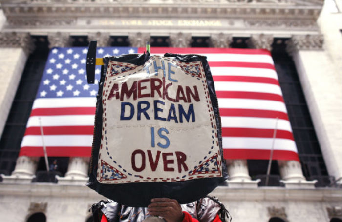 A demonstrator on Wall Street holds a sign announcing the end of the American Dream.