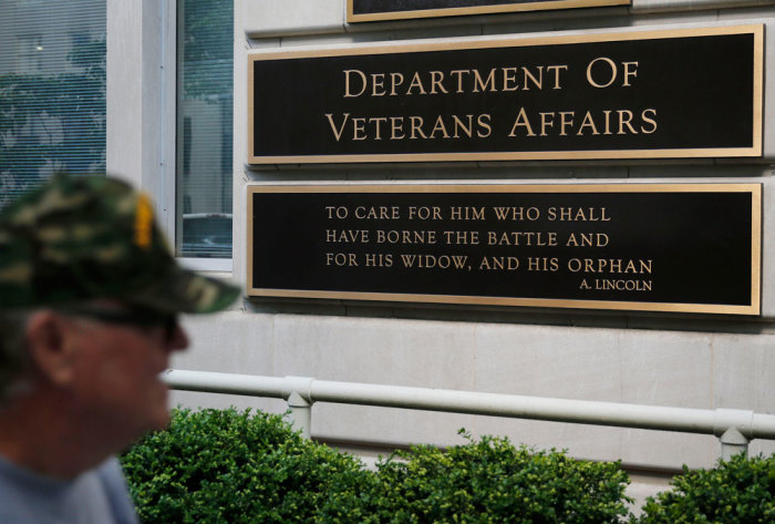 The sign in the front of the headquarters building at the Department of Veteran Affairs is seen as a man walks past in Washington, May 23, 2014.
