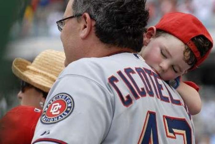 Gaetano Cicotello, age 2, catches a nap on his father Tom Cicotello's shoulder during the seventh inning stretch in a MLB interleague baseball game between the Toronto Blue Jays and Washington Nationals in Washington, June 21, 2009.