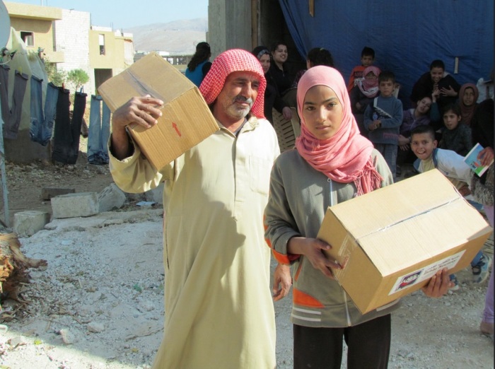 A Syrian man and girl carry Lebanon Bible Society aid packages. The Bible Society provides aid for around 3,000 Syrian refugee families.