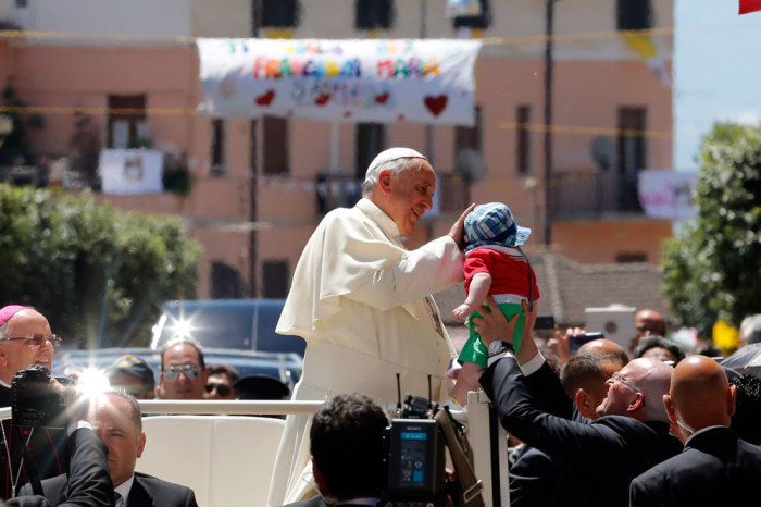 Pope Francis caresses a baby as he arrives to visit a cathedral in Cassano allo Jonio, southern Italy, June 21, 2014.