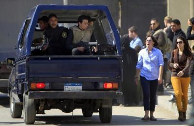 Foreign journalists and relatives of Al-Jazeera journalists walk near a police vehicle outside Cairo's Tora prison, where the trial of Al Jazeera journalists and other foreign media is due to take place, February 20, 2014.