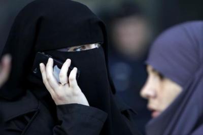 A women, wearing a niqab despite a nationwide ban on the Islamic face veil, gives a phone call outside the courts in Meaux, east of Paris, September 22, 2011.