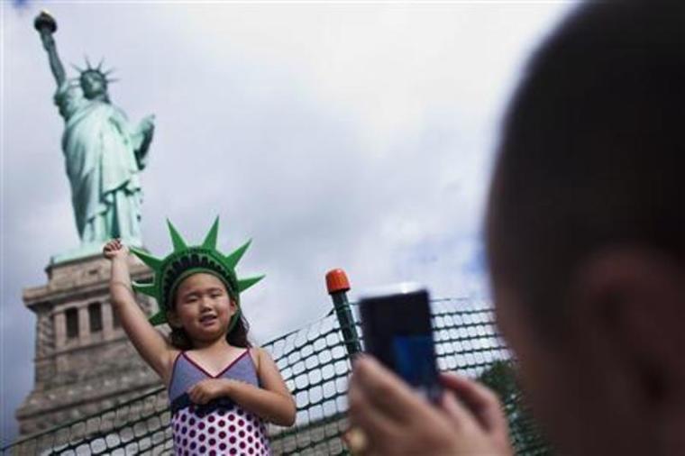 A girl poses for her father as they visit the Statue of Liberty and Liberty Island during its reopening to the public in New York, July 4, 2013.