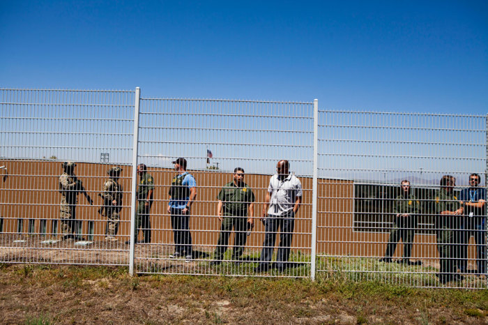 Border Patrol agents watch as demonstrators picket against the possible arrivals of undocumented migrants who may be processed at the Murrieta Border Patrol Station in Murrieta, California July 1, 2014. Some 140 undocumented immigrants, many of them women with children, will be flown from Texas to California and processed through a San Diego-area U.S. Border Patrol station as federal officials deal with a crush of Central American migrants at the border, a local mayor said on Monday.