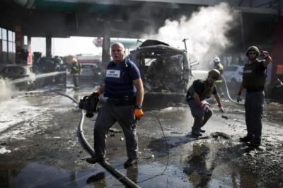 Israeli police explosive experts survey the scene at a petrol station after it was hit by a rocket in the southern city of Ashdod July 11, 2014.