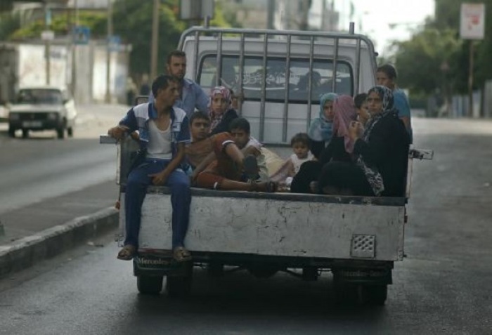 Palestinians, who fled their homes that are adjacent to the border with Israel, ride in a truck as they make their way to stay in a United Nations-run school in Gaza City July 13, 2014.