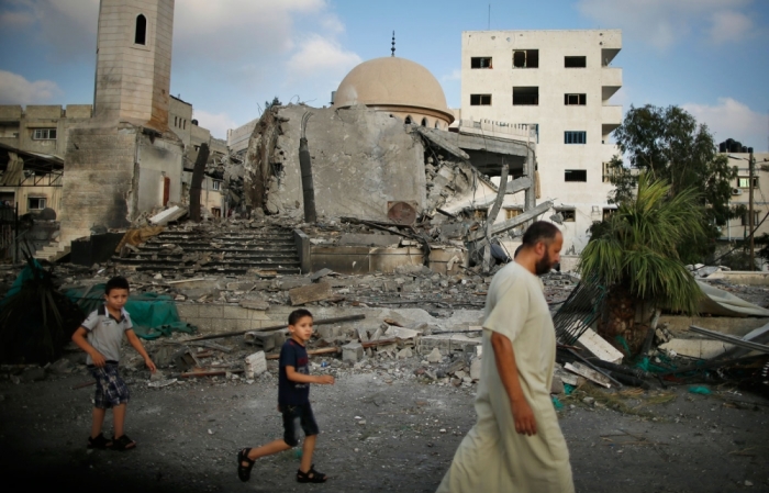 Palestinians walk past the ruins of a mosque, which police said was hit in an Israeli air strike, in Gaza City July 22, 2014. Israel pounded targets across the Gaza Strip on Tuesday, saying no ceasefire was near as top U.S. and United Nations diplomats pursued talks on halting the fighting that has claimed more than 600 lives. Hamas, the dominant group in the Gaza Strip, and its allies fired more rockets into Israel, triggering sirens in Tel Aviv. One hit a town on the fringes of Ben-Gurion International Airport, lightly injuring two people, officials said.