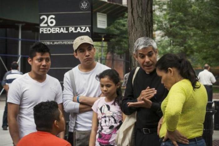 Father Fabian Arias, (2nd R) an advocate with the New Sanctuary Coalition of New York City, an immigration advocacy group, speaks with immigrants following their immigration hearings at the U.S. Federal Building in New York, in this July 10, 2014 file photo.