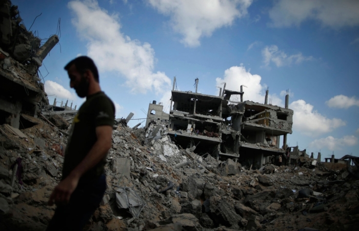 A Palestinian man walks atop the rubble of his destroyed house in the Shejaia neighbourhood, which witnesses said was heavily hit by Israeli shelling and air strikes during Israeli offensive, in Gaza City July 26, 2014. A 12-hour humanitarian truce went into effect on Saturday after Israel and Palestinian militant groups in the Gaza Strip agreed to a U.N. request for a pause in fighting and efforts proceeded to secure a long-term ceasefire moved ahead.