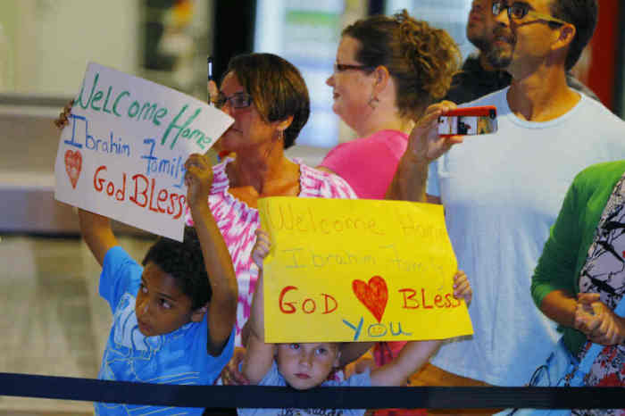 A boy holds a sign welcoming Mariam Yahya Ibrahim at the airport in Manchester, New Hampshire July 31, 2014.