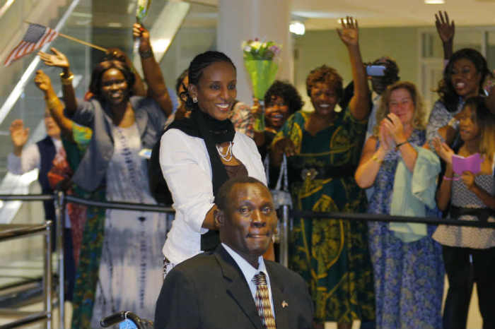 Mariam Yahya Ibrahim (C) and her husband Daniel Wani (bottom) are greeted by a cheering crowd of people as they arrive at the airport in Manchester, New Hampshire July 31, 2014.