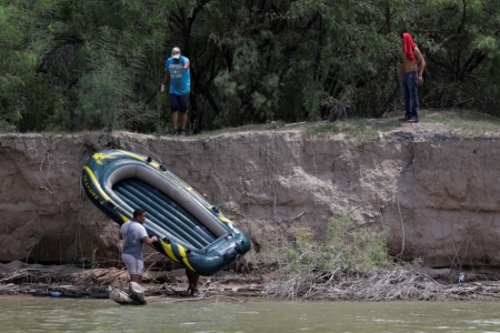 Unidentified men pull a raft to shore on the Mexico side of the Rio Grande along the U.S.-Mexico border near Mission, Texas, July 24, 2014. The Texas Department of Public Safety is fighting an uphill battle in the war against smuggling on the Rio Grande river at the U.S.-Mexico border in southern Texas.