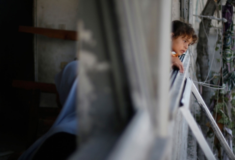 A Palestinian girl looks out the window of her family's house, which witnesses said was damaged in an Israeli air strike, in Gaza City August 2, 2014. Hamas claimed responsibility on Saturday for a deadly Gaza Strip ambush in which an Israeli army officer may have been captured, but said the incident likely preceded and therefore had not violated a U.S.- and U.N.-sponsored truce. Palestinian officials say 1,650 Gazans, most of them civilians, have been killed, including a muezzin who died in an Israeli strike on a northern mosque on Saturday. Sixty-three Israeli soldiers have been killed, and Palestinian shelling has killed three civilians in Israel. Israel launched a Gaza air and naval offensive on July 8 following a surge of cross-border rocket salvoes by Hamas and other Palestinian guerrillas, later escalating into ground incursions centred along the tunnel-riddled eastern frontier of the enclave but often pushing into residential areas.