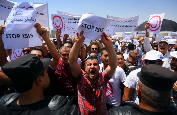 Demonstrators hold signs during a protest against militants of the Islamic State, formerly known as the Islamic State in Iraq and the Levant in Arbil, north of Baghdad July 24, 2014. Hundreds of Iraqi Christians marched to the United Nations office in Arbil city on Thursday calling for help for families who fled in the face of threats by Islamic State militants.