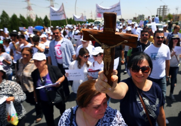 A Christian woman carries a cross during a demonstration against militants of the Islamic State, formerly known as the Islamic State in Iraq and the Levant, in Arbil, north of Baghdad July 24, 2014. Hundreds of Iraqi Christians marched to the United Nations office in Arbil city on Thursday calling for help for families who fled in the face of threats by Islamic State militants.