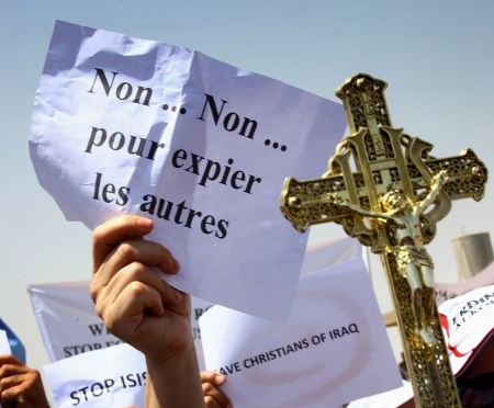 A protester carries a cross during a demonstration against militants of the Islamic State, formerly known as the Islamic State in Iraq and the Levant in Arbil, north of Baghdad July 24, 2014. The sign reads as "No... no... to atone others."
