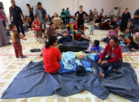 Christian families, who fled from violence in Mosul, gather inside a building which was used as a social club in Arbil, in Iraq's Kurdistan region June 26, 2014. Iraqi forces launched an airborne assault on rebel-held Tikrit on Thursday with commandos flown into a stadium in helicopters, at least one of which crashed after taking fire from insurgents who have seized northern cities.