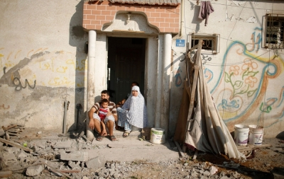 Palestinians sit outside their damaged house as they look at a neighbouring house, which witnesses said was destroyed in an Israeli air strike, in Gaza City August 9, 2014.