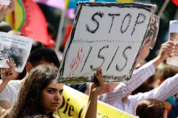 A Kurdish protester of the Yazidis ethnic minority holds a placard against Islamic State (IS) militants during a demonstration in Frankfurt August 9, 2014. Some 2,000 ethnic Kurds of the Yazidis sect, who practice an ancient faith related to Zoroastrianism, protested in the western German city on Saturday against IS militants, who are surging across northern Iraq near the Kurdistan borders in their drive to eradicate unbelievers such as Christians and Yazidis.