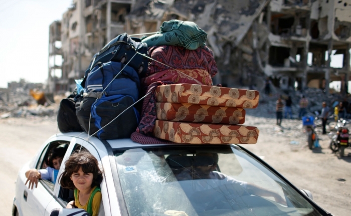 Palestinians ride in a car as they return to their house during a 72-hour truce in Beit Lahiya town, which witnesses said was heavily hit by Israeli shelling and air strikes during Israeli offensive, in the northern Gaza Strip August 11, 2014. Israeli negotiators were due in Cairo on Monday for talks on ending a month-old Gaza war with Palestinian militants, an Israeli government official said, after a new 72-hour truce brokered by Egypt appeared to be holding.