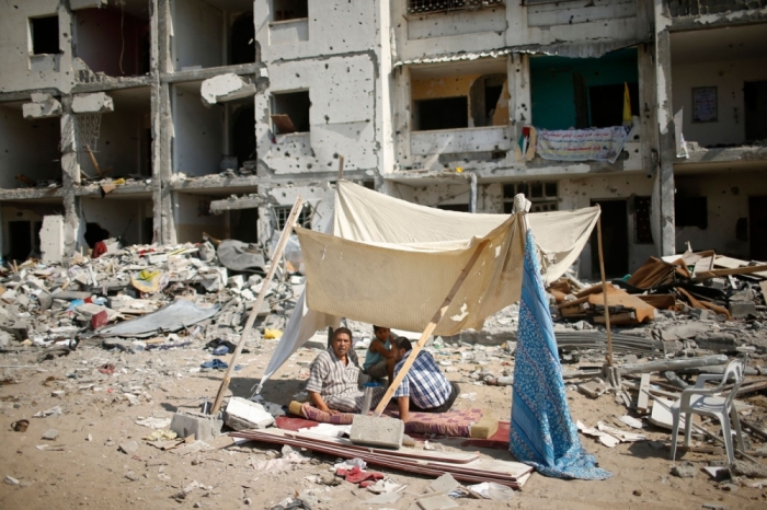 Palestinians sit in a tent as they return to their apartments in badly damaged residential buildings during a 72-hour truce in Beit Lahiya town, which witnesses said was heavily hit by Israeli shelling and air strikes during Israeli offensive, in the northern Gaza Strip August 11, 2014. Israeli negotiators were due in Cairo on Monday for talks on ending a month-old Gaza war with Palestinian militants, an Israeli government official said, after a new 72-hour truce brokered by Egypt appeared to be holding.