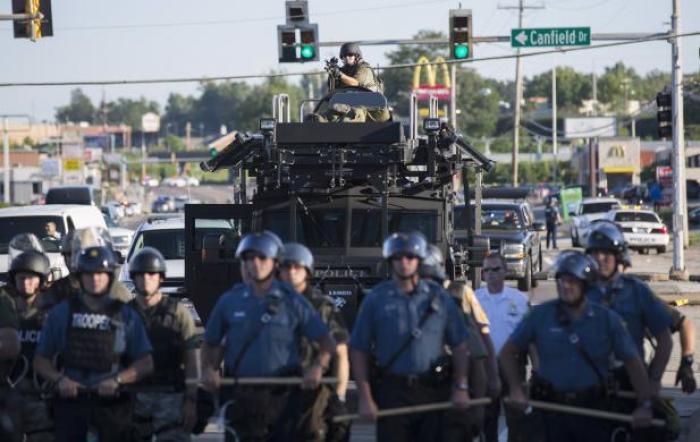 Riot police stand guard as demonstrators protest the shooting death of teenager Michael Brown in Ferguson, Missouri, August 13, 2014.