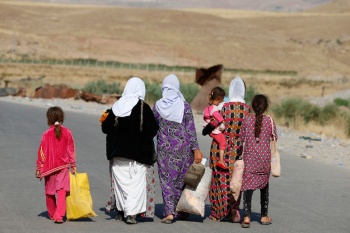 Women and children from the minority Yazidi sect, fleeing the violence in the Iraqi town of Sinjar, walk to a refugee camp after they re-entered Iraq from Syria at the Iraqi-Syrian border crossing in Fishkhabour, Dohuk province, August 14, 2014.
