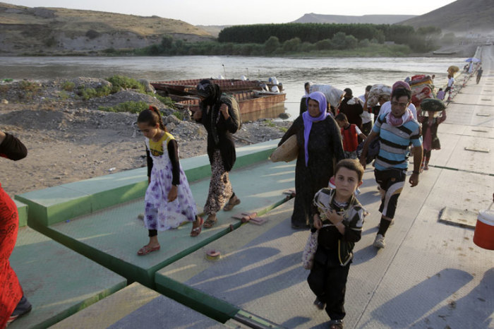 Displaced people from the minority Yazidi sect, fleeing the violence in the Iraqi town of Sinjar, re-enter Iraq from Syria at the Iraqi-Syrian border crossing in Fishkhabour, Dohuk province, August 14, 2014.