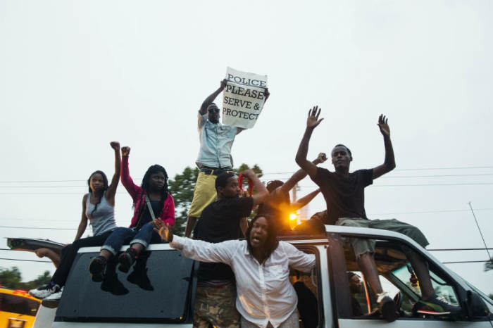 Protesters raise their hands as they drive past in a van during a demonstration to protest the shooting of Michael Brown and the resulting police response in Ferguson, Missouri, August 15, 2014.