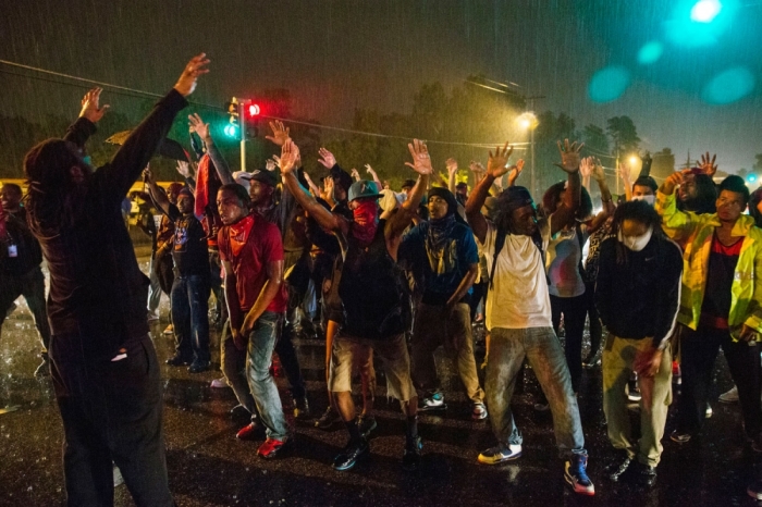 Protesters gesture as they stand in a street in defiance of a midnight curfew meant to stem ongoing demonstrations in reaction to the shooting of Michael Brown in Ferguson, Missouri August 17, 2014. The group of protesters angry at the shooting death of Brown, a black teenager, by a white police officer remained on the streets of Ferguson, Missouri, early on Sunday minutes past the declared curfew, as police began to clear the streets in a tense standoff.