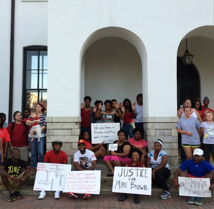 People gather for a National Moment of Silence peace vigil after unarmed teen Michael Brown was shot by a police officer in Ferguson, Missouri, at the city courthouse in downtown Oxford Squre in Oxford, Mississippi, on Thursday, August, 14, 2014.