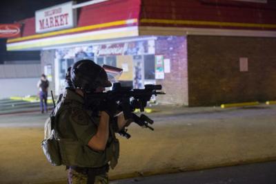 Police officers react at the scene of a looting at the Dellwood Market after protests against the shooting of Michael Brown turned violent near Ferguson, Missouri, Aug. 17, 2014.