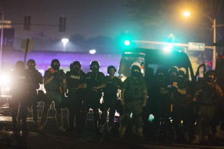 Police officers line up across the street as they maintain their distance from protesters during on-going demonstrations to protest against the shooting of Michael Brown, in Ferguson, Missouri, Aug. 16, 2014.